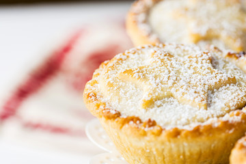 Traditional British Christmas Pastry Dessert Home Baked Mince Pies with Apple Raisins Nuts Filling on White Elegant Cake Stand. Golden Shortcrust Powdered. Festive Table Setting