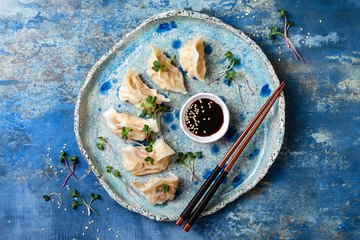 Asian dumplings with soy sauce, sesame seeds and microgreens. Traditional chinese dim sum dumplings. Copy space, flat lay - obrazy, fototapety, plakaty