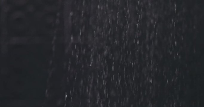 Water drops in hand. Shower or rain water drops falls in a female hand in slow motion 120fps. on a black background. Slow motion 240 fps, dolly shot, HD. 