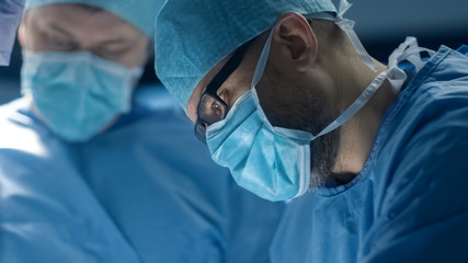 Portrait of Focused and Concentrated Surgeon Performing Surgical Operation in Modern Operating Room.