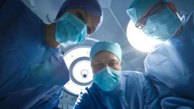 Low Angle Shot Of Team Of Doctors And Nurses Looking Into Camera. Patient Point Of View.