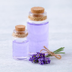 glass bottles aromatherapy oil and fresh lavender flowers on wooden table