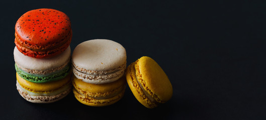 Close up French or Italian macaron on black isolate background for web design banner or cover. Homemade delicious macaron on granite table with copy space. French dessert for served with tea or coffee