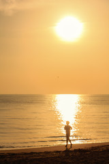 single guy jogging with bare feet on beach in sunshine day