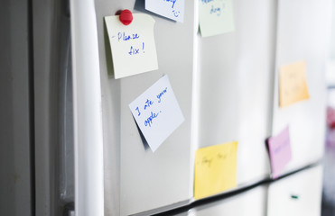 Closeup of reminder paper note on fridge door