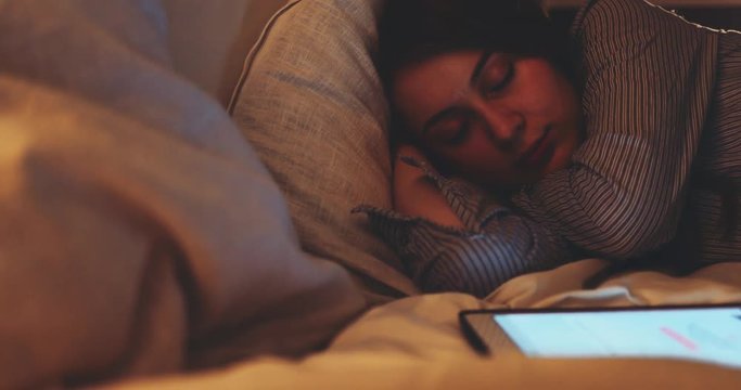 Woman Sleeping with Lights on at Night. SLOW MOTION 4K DCi. Young woman fell asleep while using digital tablet. Tired person.