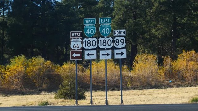 Road signs along historic US Route 66 with passing cars