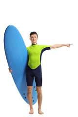 Teenage surfer holding a surfboard and pointing