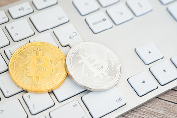 Golden and silver bitcoins on a keyboard