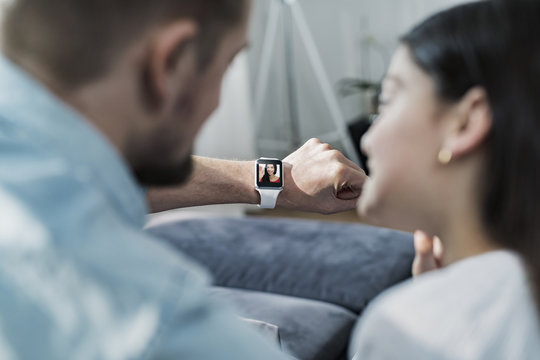 Daughter and father looking at smartwatch with mother waving at them