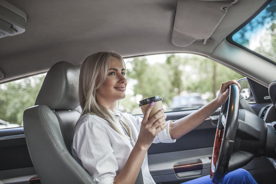 Smiling businesswoman holding takeaway coffee driving car