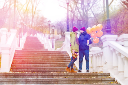 Boyfriend with orange balloons have dating with girlfriend in park in autumn. Couple in love