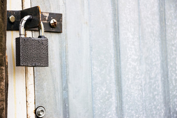 Small closed padlock hanging on the hinges