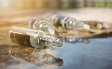 A bottle of wine is located on a wet cement floor.