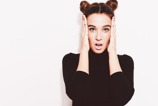 Pretty girl with buns holding hands at face.