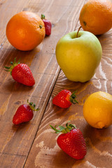 Healthy seasonal fruits on wooden background, strawberries, oranges, apple and lemon 2