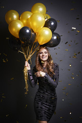 Shot of smiley woman holding bunch of balloons