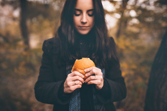 The concept of hunger and poverty. A roll or hamburger in the girls hands of a close-up.