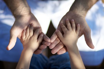 Un père tenant les mains de son fils, lien fort entre les générations pour le futur