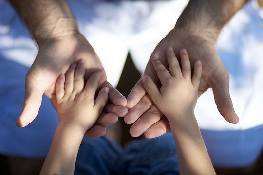 Un père tenant les mains de son fils, lien fort entre les générations pour le futur - Powered by Adobe