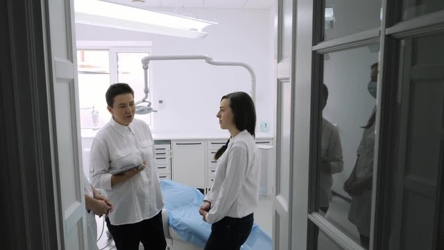 Dentist talking with young female patient in at the dentist clinic.