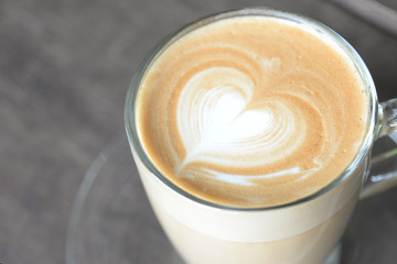 hot coffee latte with beautiful foam art heart shape on wooden table at coffee shop