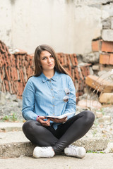 Beautiful teenage girl sitting and reading book on the rustic place