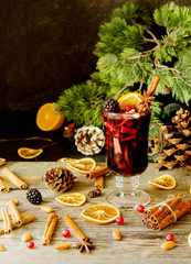 glass of hot mulled wine for the new year with ingredients for cooking, nuts and Christmas decorations