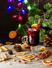 Fototapeta na wymiar glass of hot mulled wine for the new year with ingredients for cooking, nuts and Christmas decorations