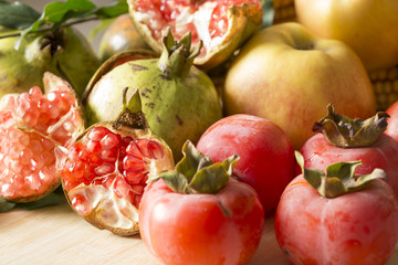 Closeup of  autumn fruit,pomegranate, apple, And persimmon on wooden table. 