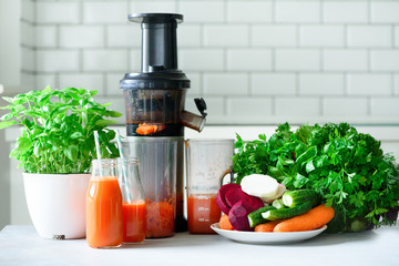 Woman making fresh drink. Juicer and carrot juice. Fruits in background. Clean eating, detox concept