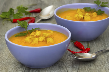 A bright cream soup of pumpkin on a gray wooden table.