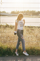 Beautiful woman walking with coffee and shopping bag in white T-shirt with word "less"