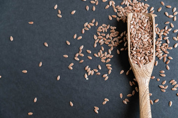 Flax seeds in spoons over dark background. Natural light. Selective focus. Close up on a black background. Top view, flat lay. copy space