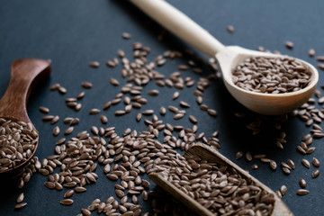 Flax seeds in spoons over dark background. Natural light. Selective focus. Close up on a black background. Top view, flat lay. copy space