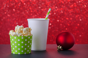 popcorn and drink in paper cup for movie and entertainment, red bokeh background, selective focus