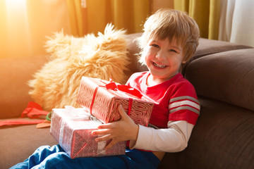 Obraz na płótnie Canvas Happy child holding Christmas presents in the morning in the room. Christmas time. Birthday..