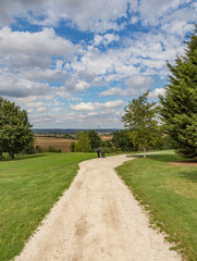 Path leading in to Golf course with golfer and trolly on the path.