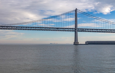 Fototapeta na wymiar Bay Bridge, San Fransisco, America with cloudy sky and calm watr