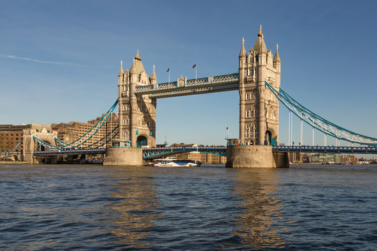 Tower Bridge in London with blue sky and reflections in the river Thames.