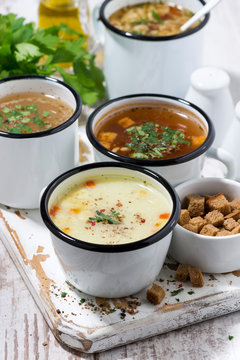 assortment of hot soups in mugs, vertical
