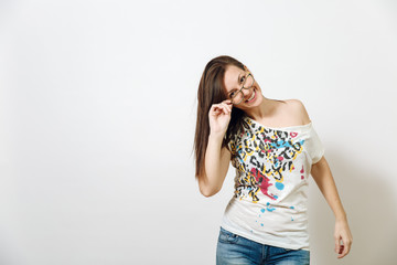 Beautiful European young smiling brown-haired woman with healthy clean skin, dressed in casual clothes standing with glasses for sight on a white background. Emotions concept.