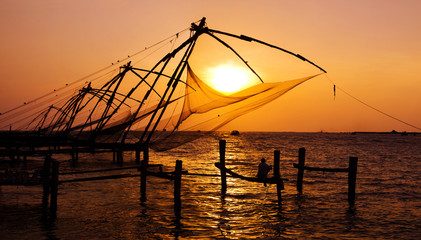 Fototapeta na wymiar Indian man fishing under the great Chinese nets at Cochin, Kerela, India.