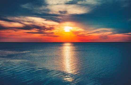 Sunset sky background. Natural Sunset Sunrise Over Ocean. Bright Dramatic Sky And Blue Water. Colorful Nature Landscape