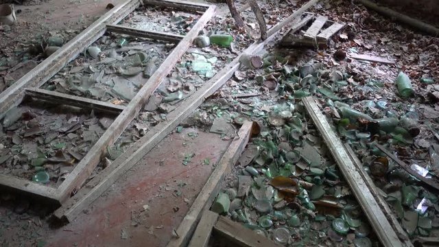Chernobyl, Ukraine - 17th of June 2017: Visit to Zalesye village in Chernobyl zone - 4K Plenty of broken bottles on the floor of abandoned house