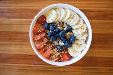 Overhead Acai bowl with fruits on wood background