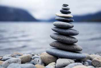 Zen balancing pebbles next to a misty lake.