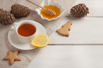 cup of hot black tea, lemon, homemade cookies and honey on white rustic wooden background. Breakfast concept, copy space
