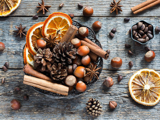 Winter ingredients nuts, cones, oranges, cinnamon star anise in a bowl. Rustic style