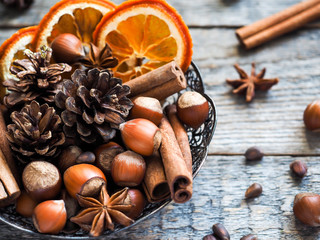 Winter ingredients nuts, cones, oranges, cinnamon star anise in a bowl. Rustic style